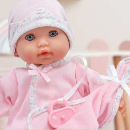 Baby doll in pink outfit with matching hat on a light background